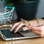 woman typing on laptop and holding a credit card
