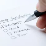 person filling out a customer satisfaction survey with pen a and paper