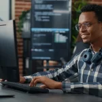 man sitting at desk typing on computer