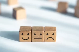 three wooded cubes lined up with different expression on them