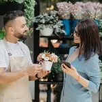 man giving a pot of flowers to a woman