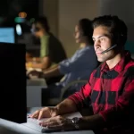 man with headset typing on keyboard